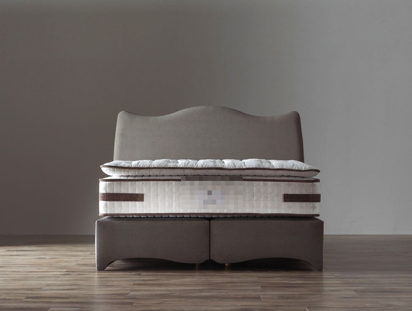 Studio product photo of a Royal Bohemia branded grey upholstered bed with curved headboard and labelled mattress