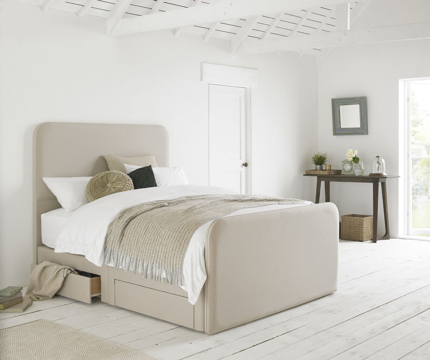 Black ribbed headboard bed styled in a bright white loft bedroom with green accent cushions