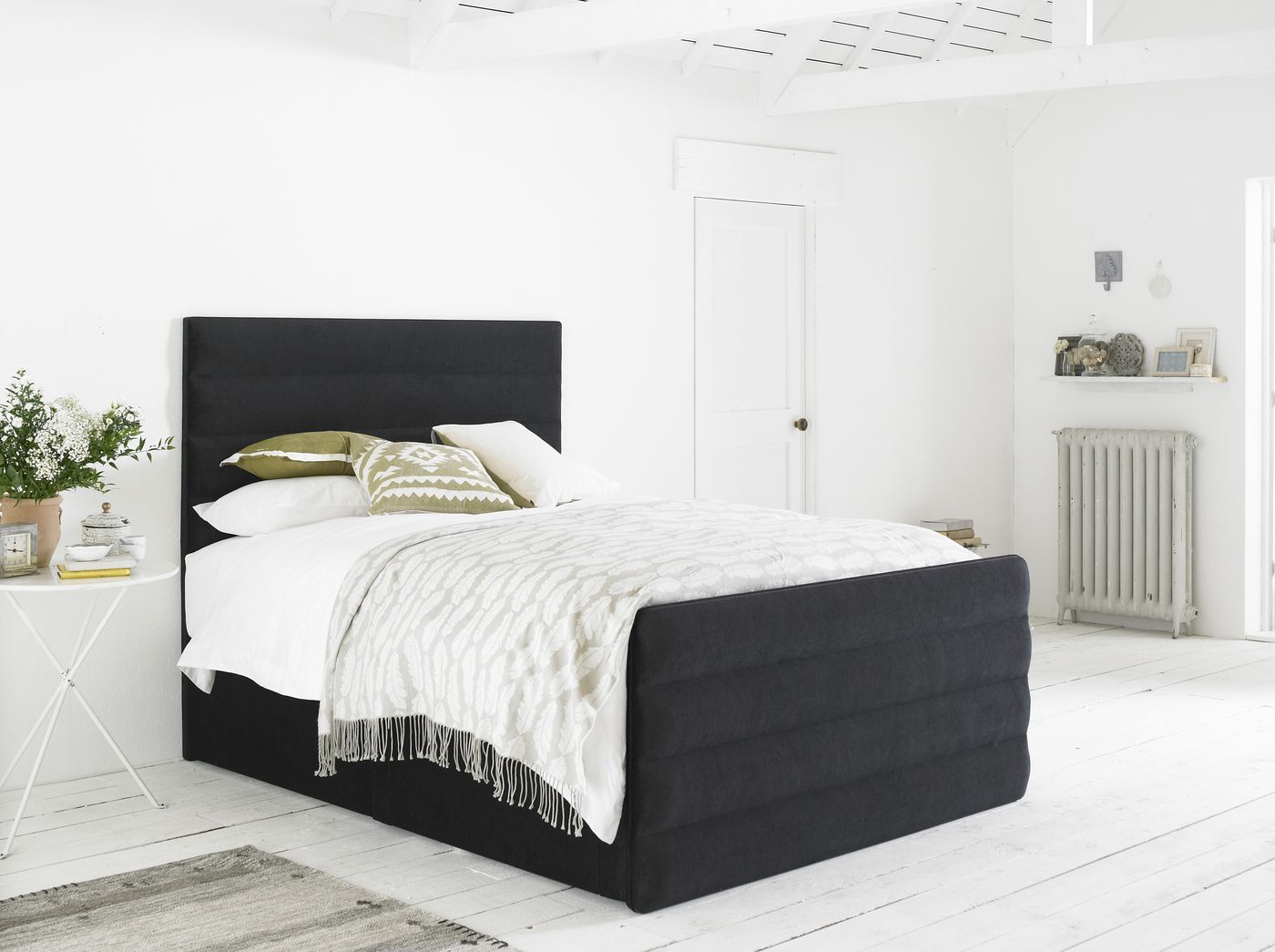 Oatmeal upholstered storage bed styled in a rustic white bedroom with an open underbed drawer